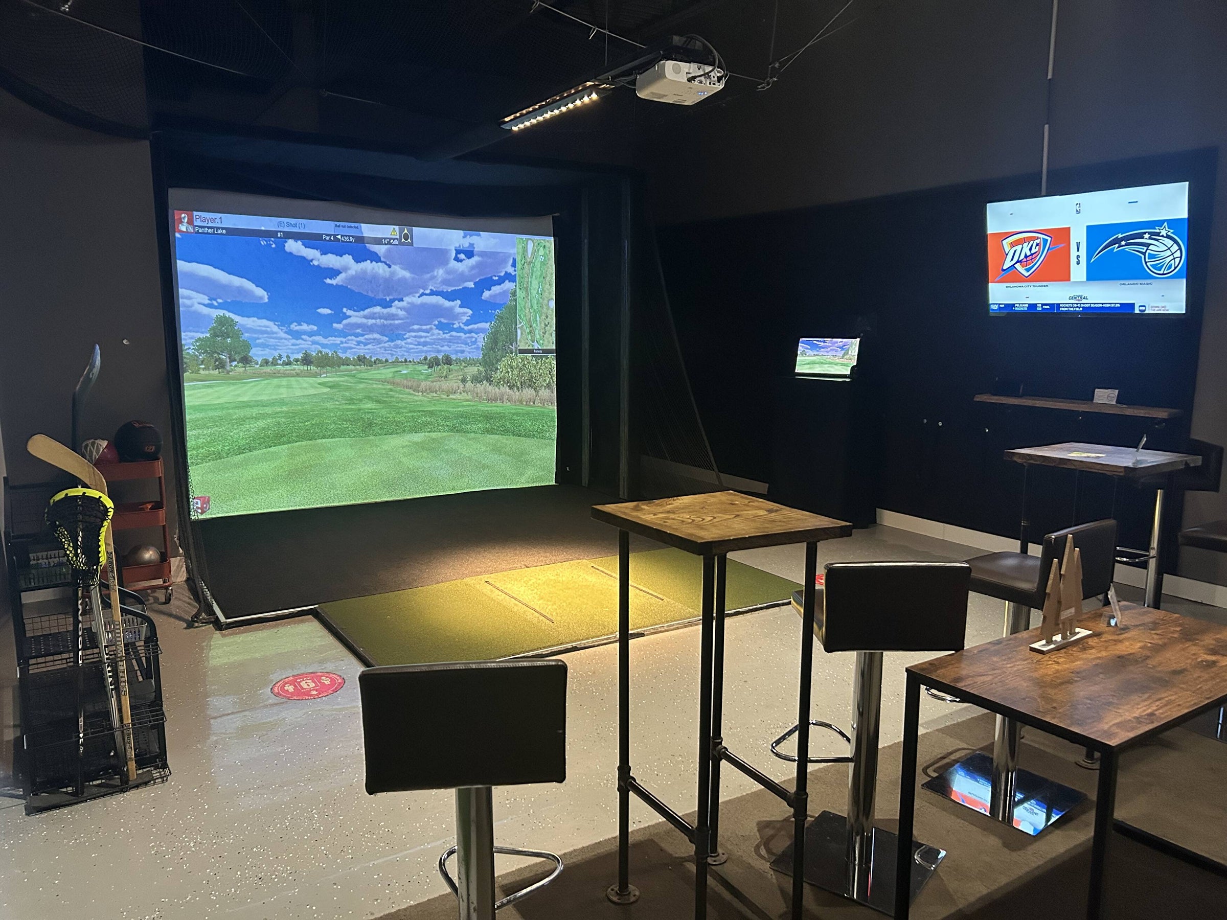 Golf simulator bay with screen, hitting area and lounge seating